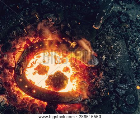 Red Fire Blazes Inside Of Coal Forge.  Blacksmith Traditional Works With Hot Metal  To Form Horse Sh