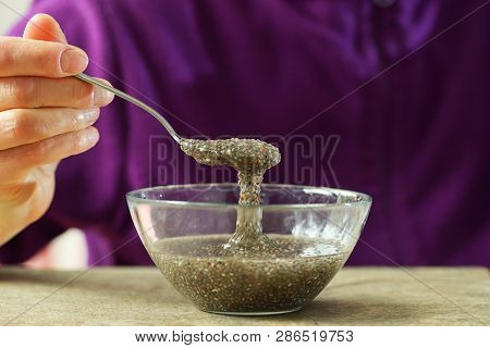 Woman Hand With Spoon Of Chia Seeds In Water
