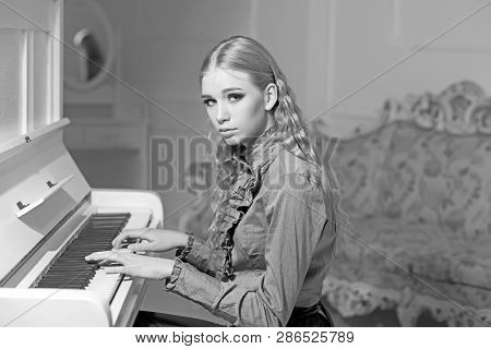 Young Victorian Girl In A Tender Blue Dress Learning To Play Piano. Lovely Blond With Curly Hair Wom