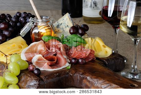 Antipasto Catering Platter With Jerky Bacon,  Prosciutto, Salami, Cheese    And Grapes On A Wooden B