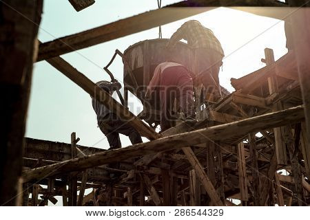 Workers Carrying The Cement Container To Pour At Site
