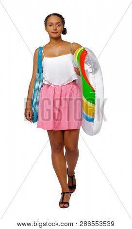 Side view of an African-American with a beach bag that goes to the side. frontside view of person. Isolated over white background. A black girl carries an inflatable circle and bag smiling.