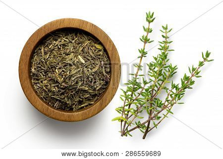 Dried Rubbed Thyme In A Dark Wood Bowl Next To Fresh Thyme Sprig Isolated On White From Above.