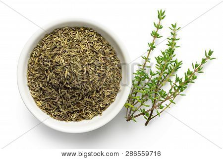 Dried Rubbed Thyme In A White Ceramic Bowl Next To Fresh Thyme Sprigs Isolated On White From Above.