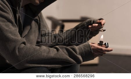 Partial View Of Narcomaniac Man Boiling Spoon With Heroin On Lighter