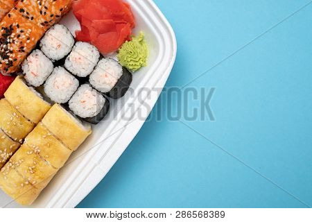 Top View On Sushi Set At Colored Background. Plate With Rolls, Ginger And Vasabi