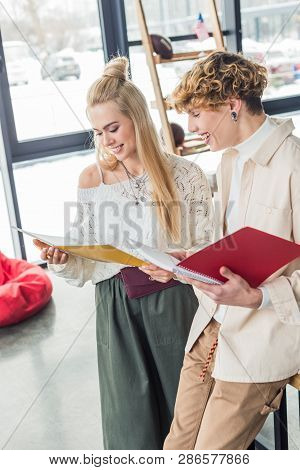 Sniling Casual Businessman And Woman Holding Notebooks And Working On Project In Loft Office