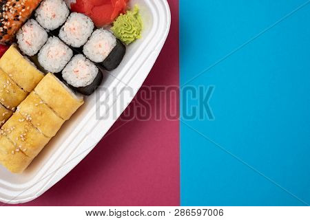 Top View On Sushi Set At Colored Background. Plate With Rolls, Ginger And Vasabi