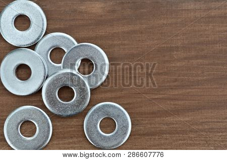 Metal Fasteners. Several Washers For Construction, Close-up On A Wooden Background.