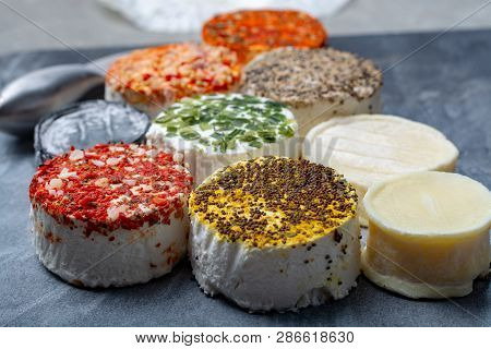 Assortment Of French Fresh White Soft Goat Cheeses With Different Tastes Topping Made With Herbs, Pa