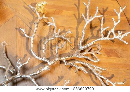 Silver Decorative  Tree Branch  Lying On Marble Tiles With Parquet, Wooden Pattern.