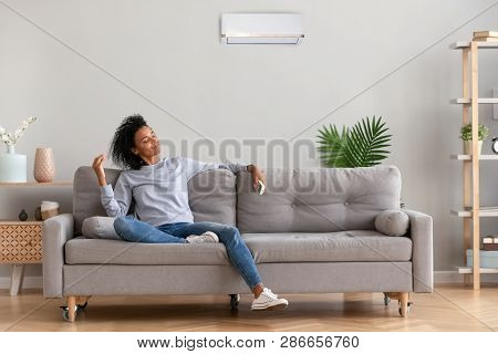 African Young Relaxed Woman Sitting On Couch Breathing Fresh Air