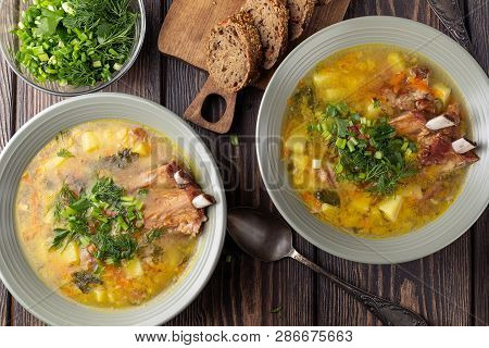 Two Plates Of Delicious Yellow Split Peas Soup With Smoked Pork Ribs  On A Wooden Table. Top View