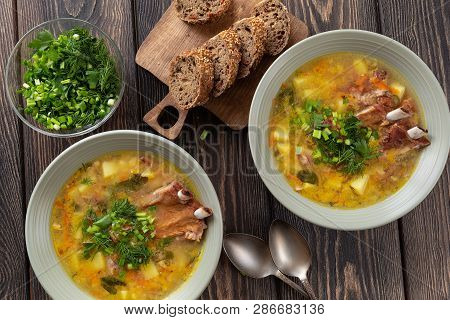 Yellow Split Pea Soup With Smoked Pork Ribs Served In Plates On A Wooden Table. Top View