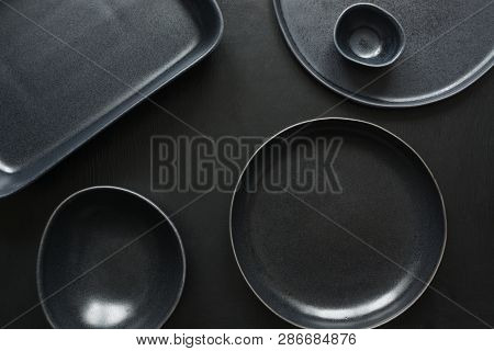 Crockery, Clayware, Black Utensils And Different Stuff On Black Tabletop. View From Above.