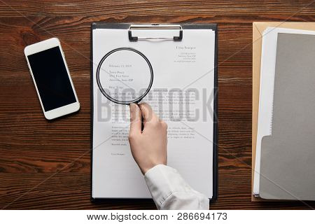Cropped View Of Businessman Reading Contract On Clipboard With Loupe