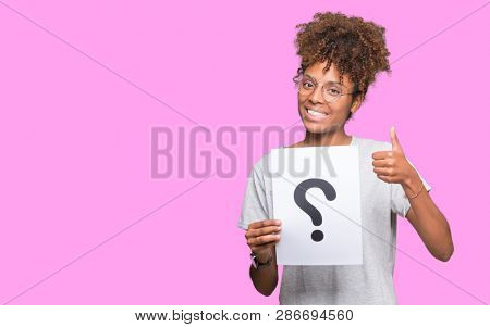 Young african american woman holding paper with question mark over isolated background happy with big smile doing ok sign, thumb up with fingers, excellent sign