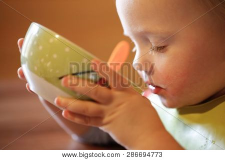 Little Boy Drinking Independently From A Bowl, Feeding Himself, Making A Mess. Early Childhood Devel