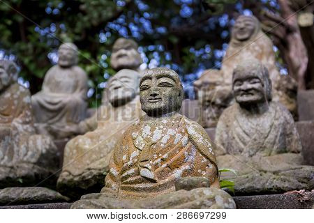 Figures Of Japanese Buddhist Monks In Close-up. Stone Statues Of Seated Monks