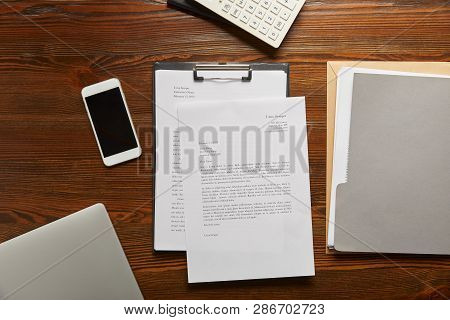 Top View Of Documets On Clipboard, Smartphone, Calculator And Folder On Table