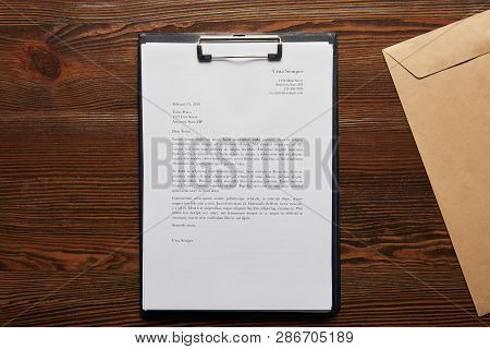 Top View Of Documet On Clipboard And Envelope On Wooden Table