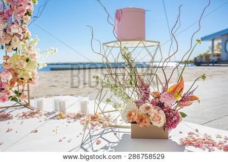 Fresh Flower Petals Lie On The Floor Next To A Decorated Wedding Arch And White Candles. Event Decor