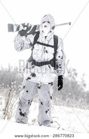 Man Soldier In The Winter On A Hunt With A Sniper Rifle In White Winter Camouflage Goes To The Field
