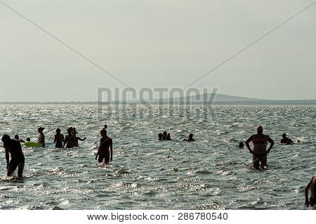 Sennoy, Russia - July 18, 2017: Taman Gulf. Silhouettes Of Group Of People Swimming In Sea