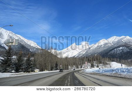 The View Through The Front Of A Car Driving Down The Highway Through The Rocky Mountains On A Sunny,