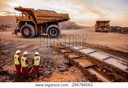 Large Dump Trucks Transporting Platinum Ore For Processing With Mining Safety Inspectors In The Fore