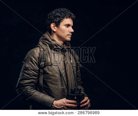 Young Handsome Traveler Posing And Stands Sideways To The Camera With His Binoculars On Black Backgr