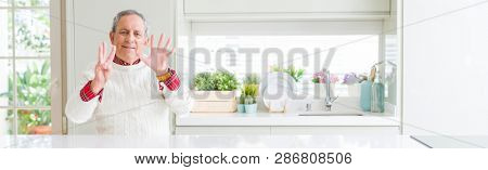 Wide angle perspective of handsome senior man at home showing and pointing up with fingers number eight while smiling confident and happy.