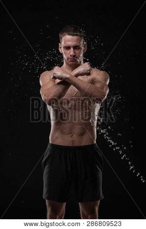 Wet Young Man Crossed His Fists, Standing In A Belligerent Pose With Water Splashes