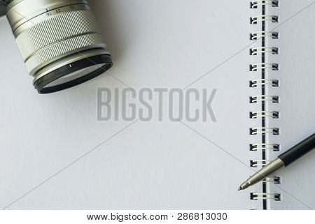 The Camera And Pen Are Placed On A White Notebook To Prepare For Work.