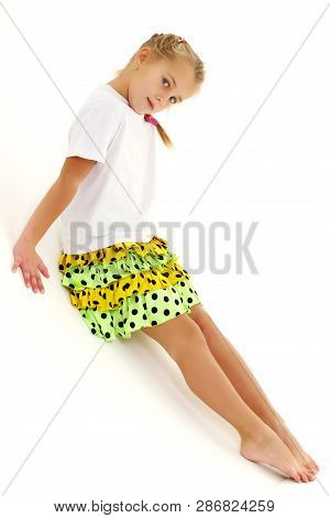 A Cute Little Girl Leaned Against A White Wall. Cyclorama In Studio. Isolated On A White Background.