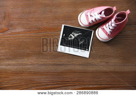 Ultrasound Picture And Baby Shoes On Wooden Background, Top View With Space For Text