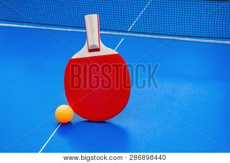 Pingpong Racket And Ball And Net On A Blue Pingpong Table