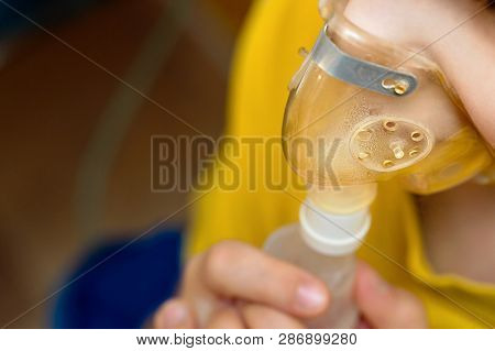 Child Makes Inhalation At Home With Nebulizer On Out Of Focus Background. Example Of Combating Respi