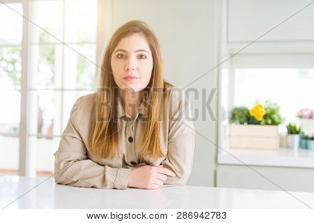 Beautiful young woman at home with serious expression on face. Simple and natural looking at the camera.