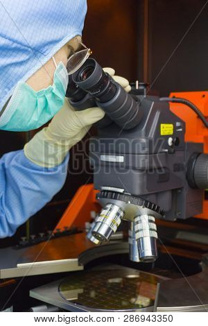 The Inspector Making Incoming Check The Silicon Wafers With Chips On Microscope In Clear Room.