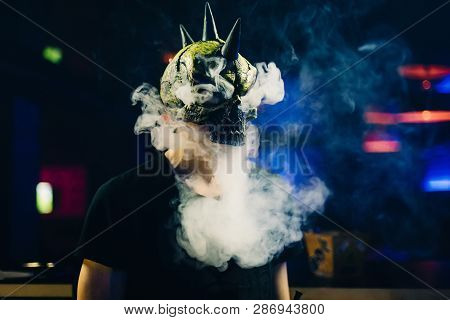 Man In A Mask Smokes A Hookah And Lets A Cloud Of Smoke