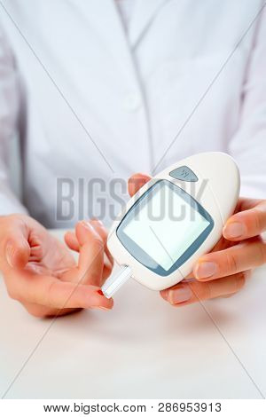 Image of doctor's hand with glucometer.