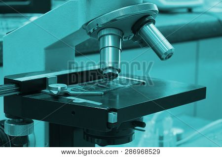 Lab Room Lit By Bactericidal Light. Microscope In The Foreground.