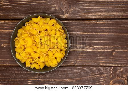 Lot Of Whole Raw Pasta Pipe Rigate Variety In A Grey Ceramic Bowl Flatlay On Brown Wood