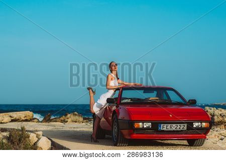 Young Beautiful Girl In Sunglasses Posing Near The Red Ferrari