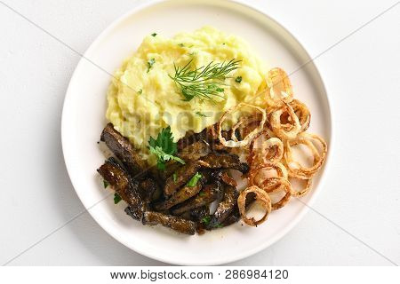 Close Up Of Roasted Beef Liver With Mashed Potatoes And Fried Onion Rings On White Plate Over Stone 