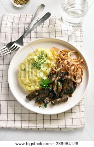 Slices Of Beef Liver With Mashed Potatoes And Fried Onion Rings On White Plate. Pieces Liver (offal)