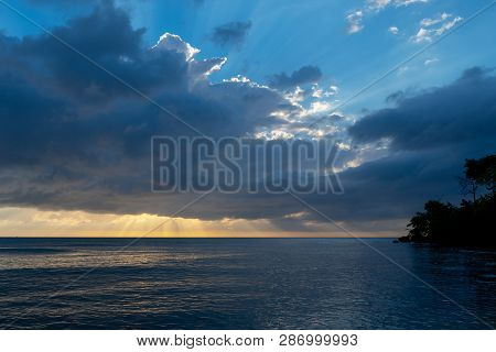 Sun Rays Beaming Through The Clouds Over The Ocean As Another Day Ends. Evening Time On Tropical Isl