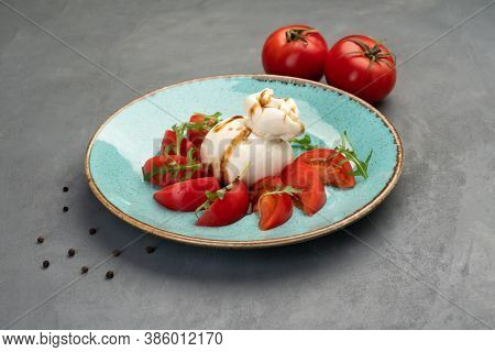 Buratto Cheese With Tomatoes And Arugula On A Blue Plate