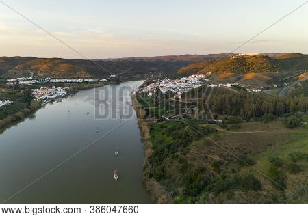 Aerial Drone View Of Sanlucar De Guadiana In Spain And Alcoutim In Portugal With Sail Boats On Guadi